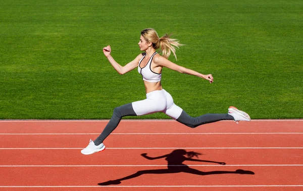 Runner. Professional sportswoman during running training session. Woman running jump on stadium track. Sportswoman in sportswear jumping.