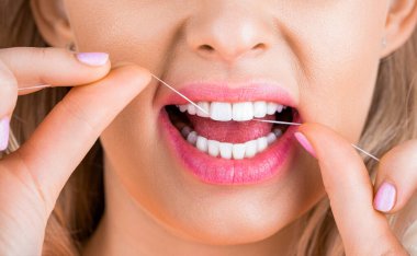 Sağlıklı diş kavramı. Diş ipiyle diş ipi. Ağız temizliği ve sağlık hizmetleri. Gülümseyen kadınlar diş ipi kullanır. Sağlıklı dişler. Diş ipi, diş ipi kullanan kadın. Diş ipi mi? Dişlerine bakıyorum..