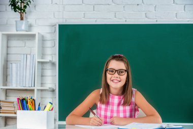 Okul konseptine geri dönelim. Tahtaya resim çizen şirin küçük kız. Sınıfında tahtada tahtası olan mutlu, güler yüzlü, tatlı bir kız öğrenci. İlkokul öğrencisi portresi..
