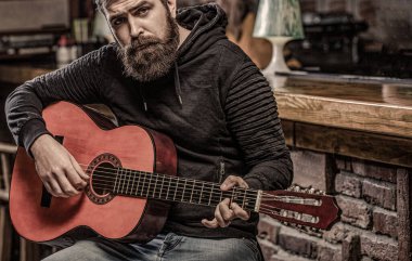 Müzik konsepti. Sakallı gitarist. Gitarlar ve teller. Gitar çalan sakallı bir adam, elinde akustik bir gitar tutuyor..