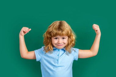 Güçlü çocuk. Okullu çocuk yeşil karatahta üzerine izole edilmiş. Küçük komik süper kahraman çocuk kaslarını gösteriyor. Güç, güven ya da zorbalığa karşı savunma. Yumruk tutan çocuk, pazı..