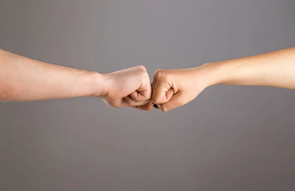 Man and woman are fist bumping. Fist Bump. Clash of two fists, vs. Gesture of giving respect or approval. Friends greeting. Teamwork and friendship. Partnership concept. Male vs female hand.