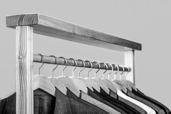 Suits for men hanging on the rack. Mens suits in different colors hanging on hanger in a retail clothes store, close-up. Black and white.