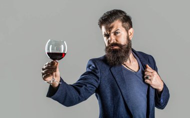 Elinde bir bardak kırmızı şarap olan bir adam. Sakallı, sakallı, şarap içen şarap garsonu. Sommelier, bir bardak şarap, şaraphane ve şarap üreticisi..
