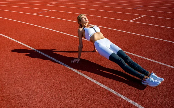 Sports exercises and stretching in the stadium. Physical training girl. Fit girl do outward lunging. Physical training education. Sports lesson. Female runner stretching before workout.