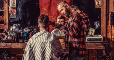 Berber dükkanını ziyaret eden bir adam. Berber saç makasıyla çalışıyor. Hipster müşteri saçını kestiriyor. Berber dükkanındaki sakallı adam. Saç kesimi konsepti.