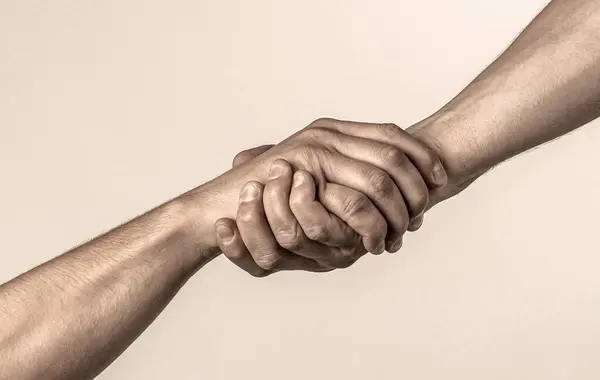 Lending a helping hand. Handshake, arms friendship. Friendly handshake, friends greeting, teamwork, friendship. Close-up. Rescue helping gesture or hands