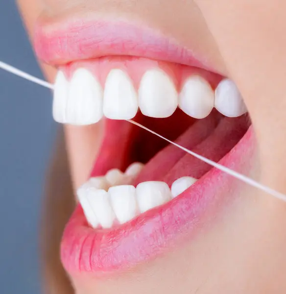Dental floss. Oral hygiene and health care. Smiling women use dental floss white healthy teeth. Dental flush - woman flossing teeths.Taking care of teeth. Teeth Flossing.