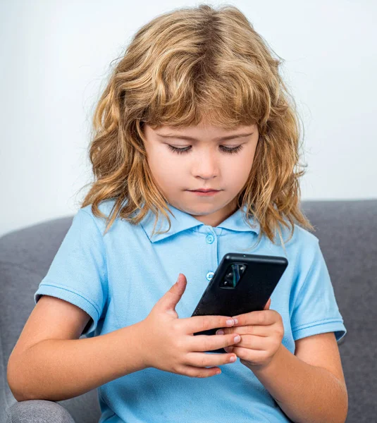 Little boy using smartphone, looking at screen, child holding phone in hands, playing mobile device game, watching cartoons online.
