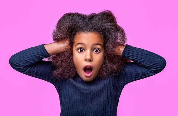 Wow. Emotional African American little girl, being surprised, shocked, showing true astonished reaction on unexpected news. Portrait of surprised little toddler girl child isolated pink background.
