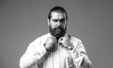 Beyaz gömlekli yakışıklı sakallı adamın portresi. Erkek sakalı ve bıyığı. Seksi erkek, vahşi maço, hippi. Siyah ve beyaz.