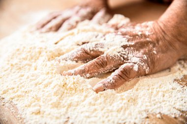Mutfakta un bulunan el fırıncısı. Una bulanmış elleri olan kadın. Kadın eli, un ve hamur. Kadın ev yapımı için hamur hazırlıyor. Beyaz pudra kaplı masa üzerindeki gübre. El unu..
