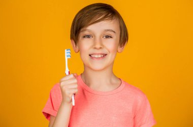 Diş hijyeni. Küçük mutlu çocuk dişlerini fırçalıyor. Çocuk dişlerini fırçalıyor. Erkek diş fırçası beyaz diş macunu. Sağlık hizmeti, diş hijyeni. Neşeli çocuk diş fırçalarını gösteriyor. Küçük çocuk diş temizliyor..