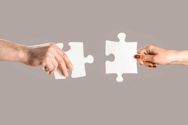 Bulmacalar. Erkek ve kadın elinde bir yapboz tutuyor. İş çözümleri, başarı ve strateji kavramı. Eller bulmacayı birbirine bağlıyor. Erkeğin ve kadının eli yapbozu katlıyor, yakın plan..