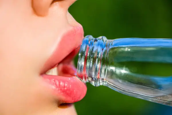 Beautiful female lips, bottle with soda. Close-up of a girl with a bottle. Natural makeup, full lip. Cute fashion summer look with bottle of water. Closeup of womans lips drinking.