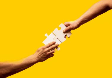 Two hands trying to connect couple puzzle piece on yellow background. Teamwork concept. Closeup hand of connecting jigsaw puzzle. clipart