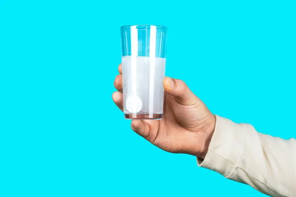 Glass of water tablet. Glass with effervescent tablet in water with bubbles. White pill and a glass of water in man hands. Health concept. Close up of man holding a pill.