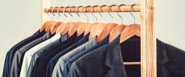 Erkek gömlekleri, takım elbise askıda asılı. Butikte üzerinde ceket olan askılar..