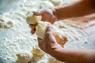 Turta yapma süreci, el. Eller turta hamuru. Hamur işleri, hamur işleri. Kadınların elleri turta için hamuru yuvarlıyor. Son sınıf öğrencisi kadın elinde oklavayla un içinde hamur topluyor..