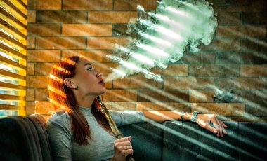 Kız nargile içiyor. Gece kulübünde ya da barda güzel bir kadın nargile ya da başka bir şey içiyor. Sigara içmenin zevki.