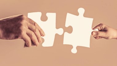 Erkeklerin ve çocukların elleri bulmacaları birbirine bağlıyor. Eller bulmacayı birbirine bağlıyor. El çocuğu ve ana yapbozunun eli, yakın plan. Eller bulmacaları tutar.