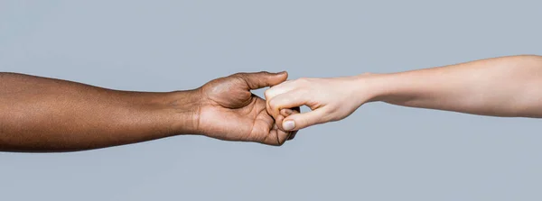 Giving a helping hand to another. Woman and african woman hand. Black and white human hands. African and caucasian hands.