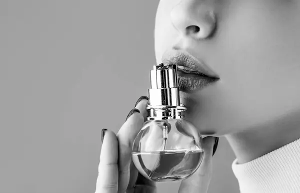 Woman with bottle of perfume. Woman presents perfumes fragrance. Sexy lips. Black and white.