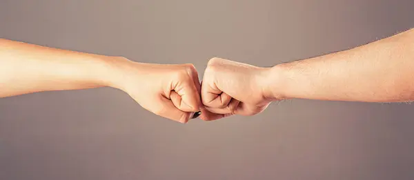 Fist Bump. Clash of two fists. Gesture of giving respect or approval. Friends greeting. Teamwork and friendship. Man and woman are fist bumping.