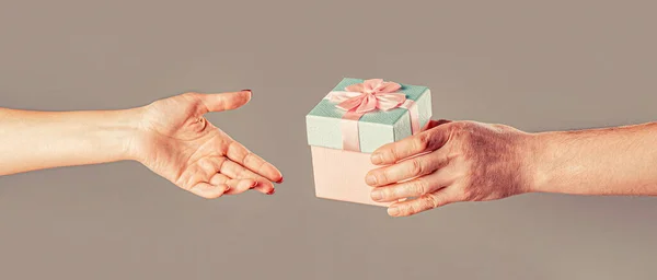Gift box in hand, surprise and holiday concept. Man hands holding valentines day gift. Girl gives a gift to man. Woman hands holding gift.