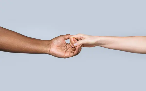 White Caucasian female hands and black african american holding fingers together. Woman and african woman hand. Helping hand, rescue. Helping hands, rescue gesture. Black and white human hands.