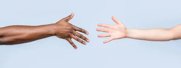 Helping hands, Rescue gesture. Black and white human hands. African and caucasian hands. Giving a helping hand to another. Woman and african woman hand.