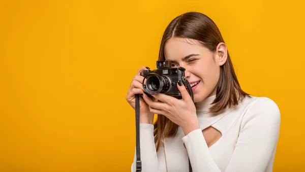 Girl with a cameras. Woman holding camera over yellow background. Girl using a camera photo. Photographing girl make photography taking concept.