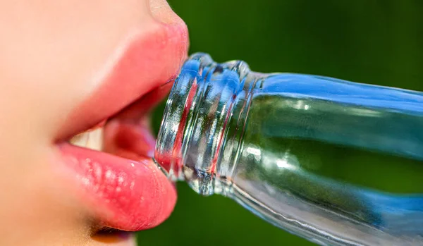 Closeup of womans lips drinking. Beautiful female lips, bottle with soda. Cute fashion summer look with bottle of water.