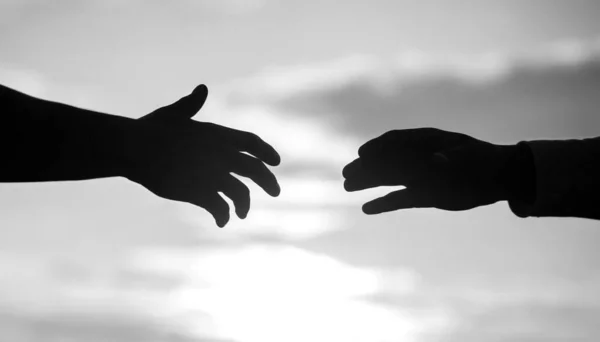 Outstretched hands, salvation, help silhouette, concept of help. Giving a helping hand. Rescue, helping gesture or hands. Black and white.