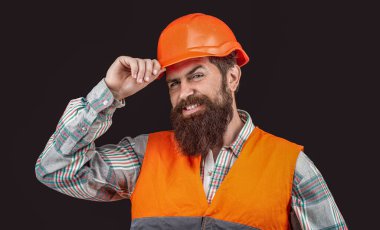Mutlu sakallı adam siyah arka planda izole edilmiş kask giyer. Mühendis ya da mimar gülümser. İnşaat, mutluluk, gelişme, meslek kavramı. Kasklı inşaatçı, ustabaşı veya miğferli tamirci..