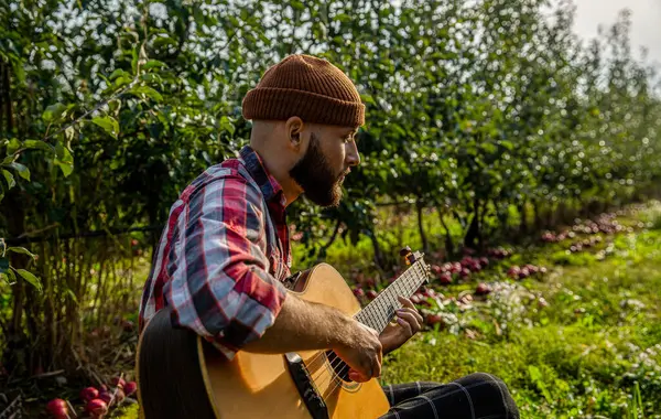Man s hand playing acoustic guitar, song. Nature background. Guitars acoustic. Male musician playing guitar, music instrument. Mans hands playing acoustic guitar.