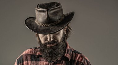 Kovboy tarzı. Kovboy şapkasını ayarlayan yakışıklı genç adam. Şapkalı kovboylar. Yakışıklı sakallı maço. Tıraşsız kovboylar. Amerikan kovboyu. Deri kovboy şapkası..