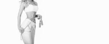 Atlama ipiyle izole edilmiş beyaz arka planı olan genç bir kadın. İnce vücut, ip atlama. Mükemmel bel ve ellerinde ip ile atlayan bir kız. Siyah ve beyaz.