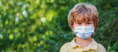 Coronavirus ve Covid salgını sırasında sokakta maske takan küçük bir çocuğun portresi - 19. Anti virüs maskesi takan çocuk. Corona virüsü covid-19 'dan korumak için maske takan çocuk..