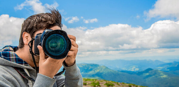 Photographer take pictures Snapshot with camera.Mens hands held camera closeup. Man hand holding camera looking through lens, shooting photographs in the mountains.