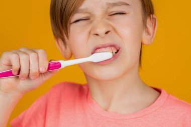 Diş hijyeni. Küçük çocuk dişlerini fırçalıyor. Çocuk dişlerini fırçalıyor. Erkek diş fırçası beyaz diş macunu. Sağlık hizmeti, diş hijyeni. Çocuk diş fırçalarını gösteriyor. Küçük çocuk diş temizliyor..