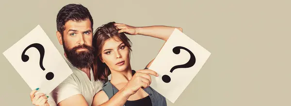 Portrait of couple holding paper question mark. Couple thinking about something. Confused couples with question marks. Conflict between two people. Pensive man and a thoughtful woman, conflict.