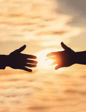 El sıkışma silueti, gün batımında el ele tutuşmalar, takım çalışması, el ele tutuşmalar. Uzanmış eller, kurtuluş, siluete yardım, konsept yardım. Yardım eli uzatıyorum. Kurtarma, yardım jestleri veya eller.