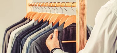 Gardırobundaki ceketi seçen adam. Erkek takımları peş peşe asılıyor. Erkek kıyafetleri, butikler. Terzi, terzilik. Şık erkek kıyafeti. Erkek kıyafeti, atölyesinde terzi. Kostüm giymiş moda adamı..