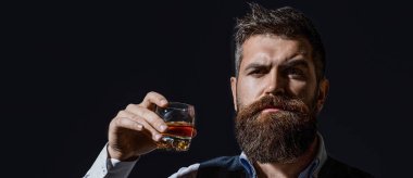 Elinde siyah arka planı olan viski bardağı tutan adam, yakın plan. Elinde viski bardağı tutan sakallı yakışıklı adam. Sakallı adam cam brendi tutuyor. Sakallı konyak. Sommelier 'in tadı içki gibi..