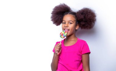 Şekerli lolipopu olan komik Afrikalı çocuk, şeker yiyen mutlu küçük kız. Kız afro, lolipoplar. Gülümse küçük Amerikalı kız lolipop yiyor, elinde pembe renkli lolipop şekeri, şekerler.