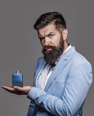 Erkek parfümü, parfüm. Parfüm ya da parfüm şişesi. Sakallı adam elinde bir şişe parfüm tutuyor. Adamın elinde kozmetik, şişede serum var, ellerine uygulanıyor. Erkek parfümü ve parfümü..