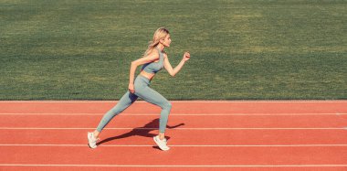 Dişi koşucu dışarıda koşuyor, koşucu. Stadyumda spor yapan kadın. Stadyum pistinde koşan genç bir fitness oyuncusu. Spor giyimli bir kadın stadyumda koşuyor..