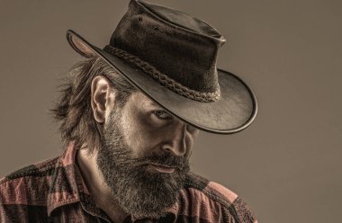 Kovboy tarzı. Kovboy şapkasını ayarlayan yakışıklı genç adam. Şapkalı kovboylar. Yakışıklı sakallı maço. Tıraşsız kovboylar. Amerikan kovboyu. Deri kovboy şapkası..