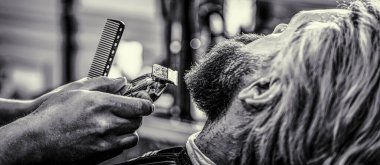 Erkek saç kesimine yakın çekim, usta berber dükkanında kuaförlük yapıyor. Sakal makası olan bir kuaförün elleri. Berber sakal makasıyla çalışıyor. Hipster müşteri saçını kestiriyor. Siyah ve beyaz.